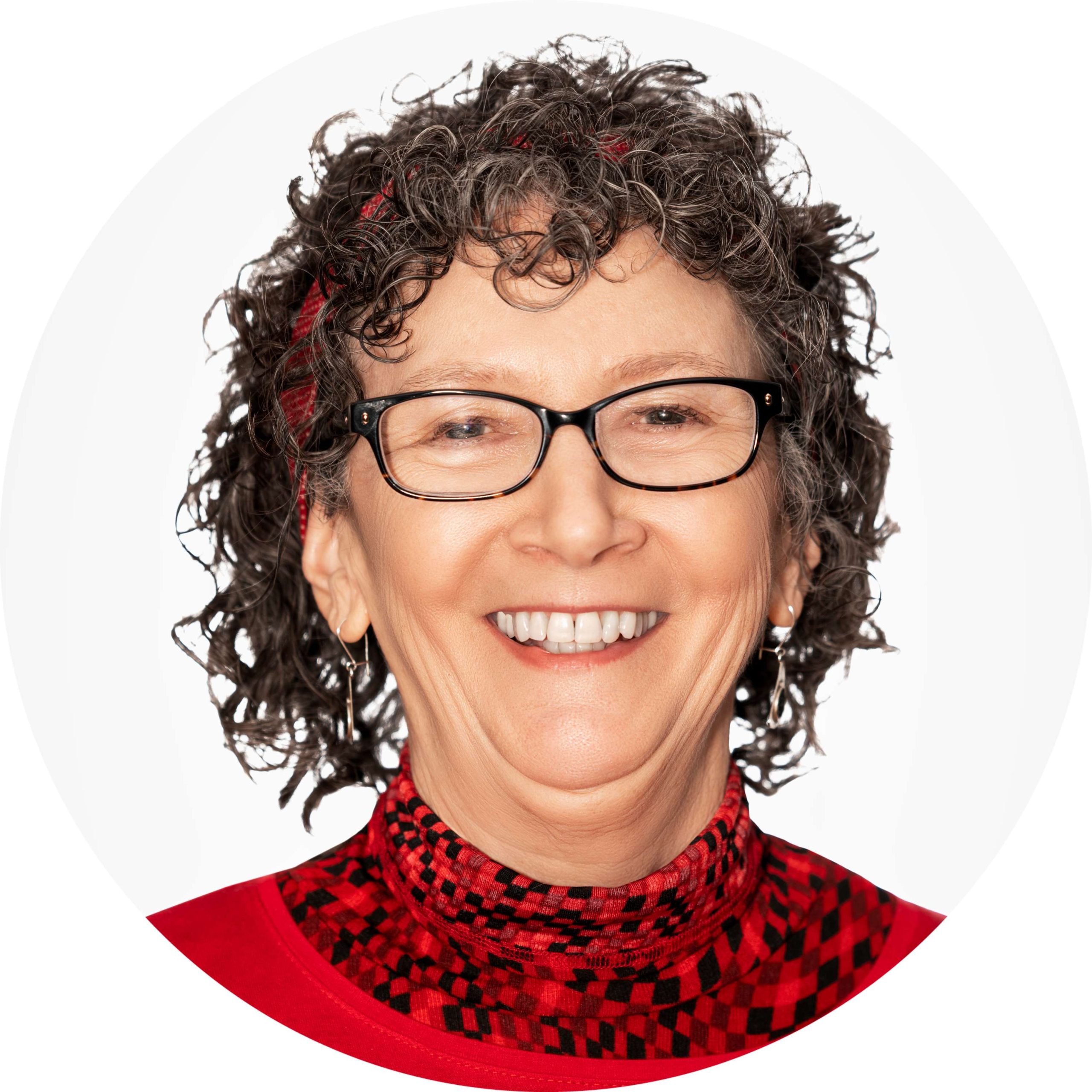 Terri Neff, female, with short curly hair, wearing glasses and a red sweater and red turtleneck